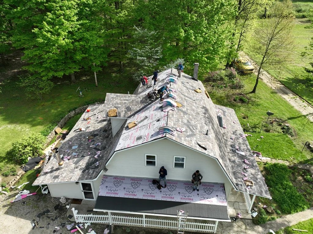 Aerial view of a roofing crew installing new asphalt shingles on a residential home.