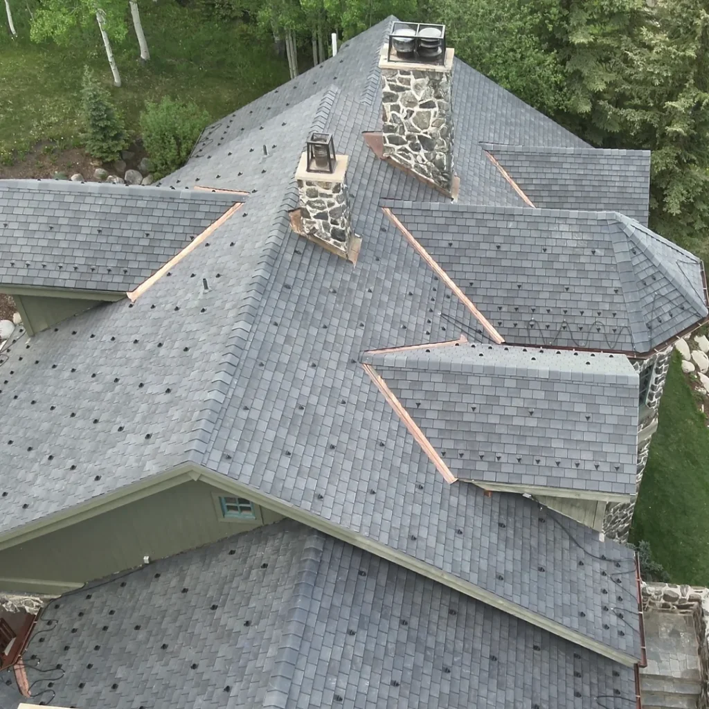 Aerial side view of F-Wave XTD shingle roof showing copper flashing around two chimneys on Snowmass Village home