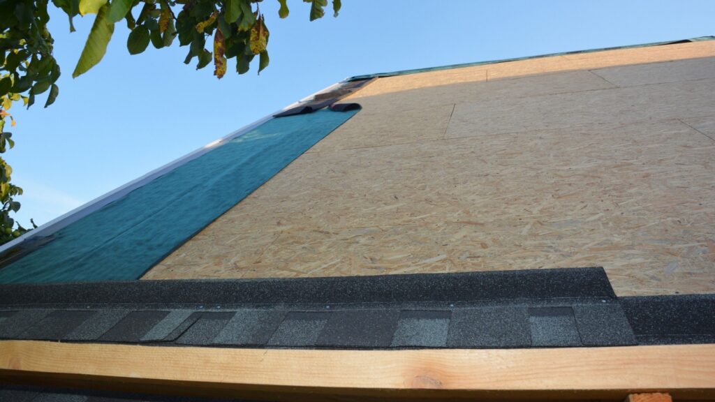 Asphalt shingles installation on plywood, roof sheathing and waterproofing synthetic roof underlayment.