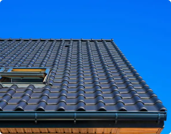 Close‑up view of a modern residential roof with dark gray ceramic tiles and a skylight under a bright blue sky in Franklin, Tennessee.