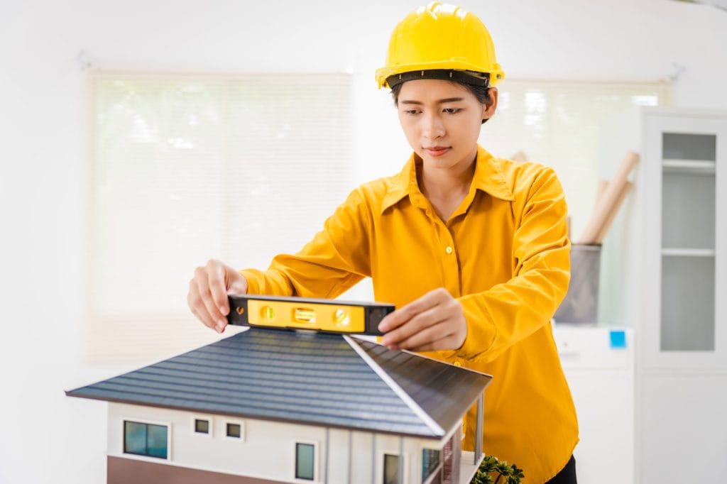 Roofing contractor assessing roofing material lifespan on a house model.