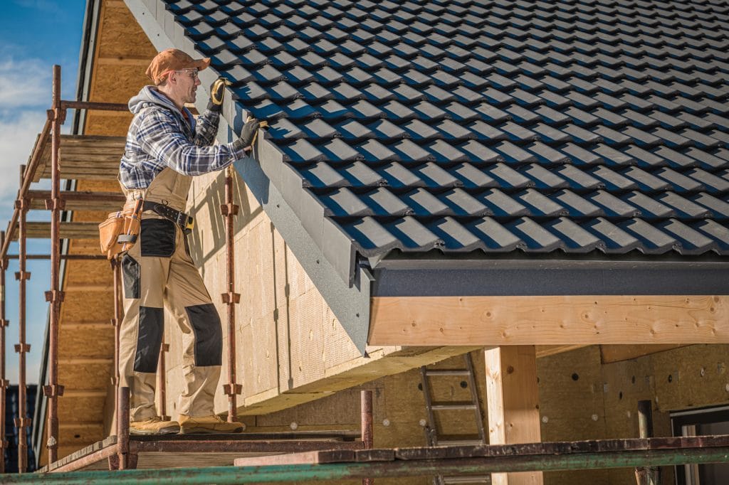 A reputable roofing contractor installing new metal tiles during a roof replacement.