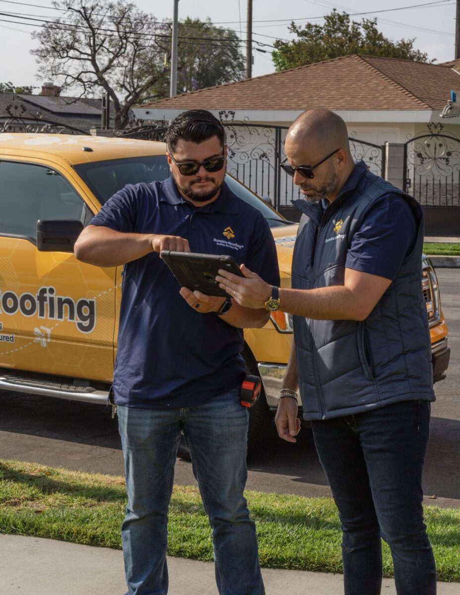 Bumble technicians having a conversation in front of a Bumble Roofing truck.