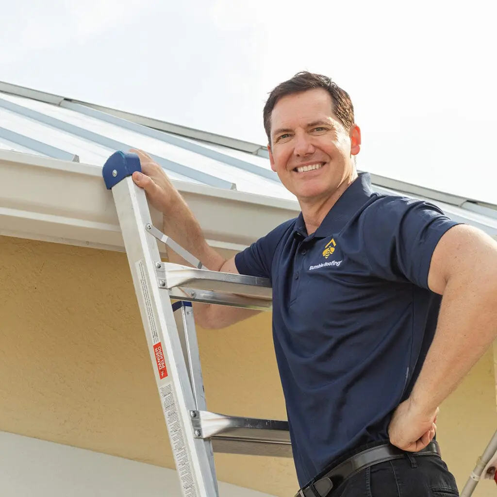 Bumble roofing worker standing on a ladder to a repaired roof