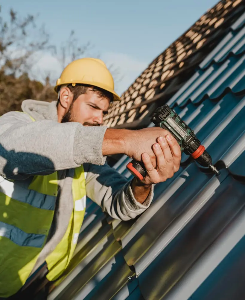 Roofer drilling new shingles into a roof