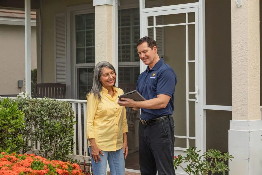 Bumble Roofing technician speaking with a woman in front of her house.